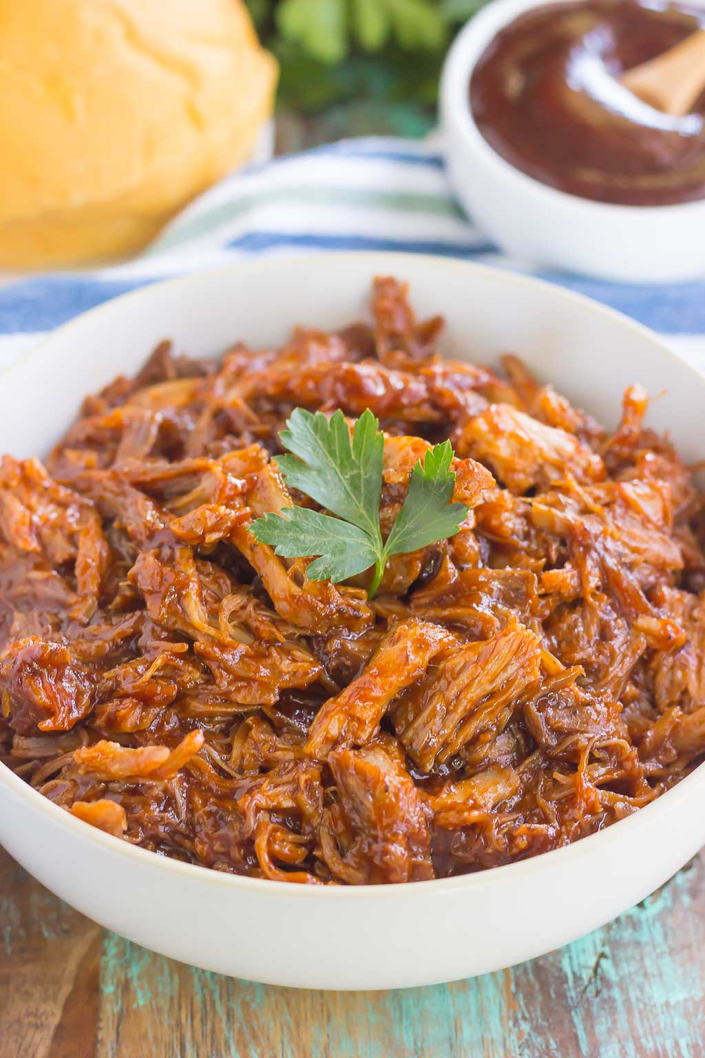 Slow Cooker Barbecue Pulled Pork garnished with fresh parsley in white bowl