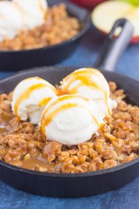 close up shot of vanilla ice cream on top of apple crisp with caramel sauce