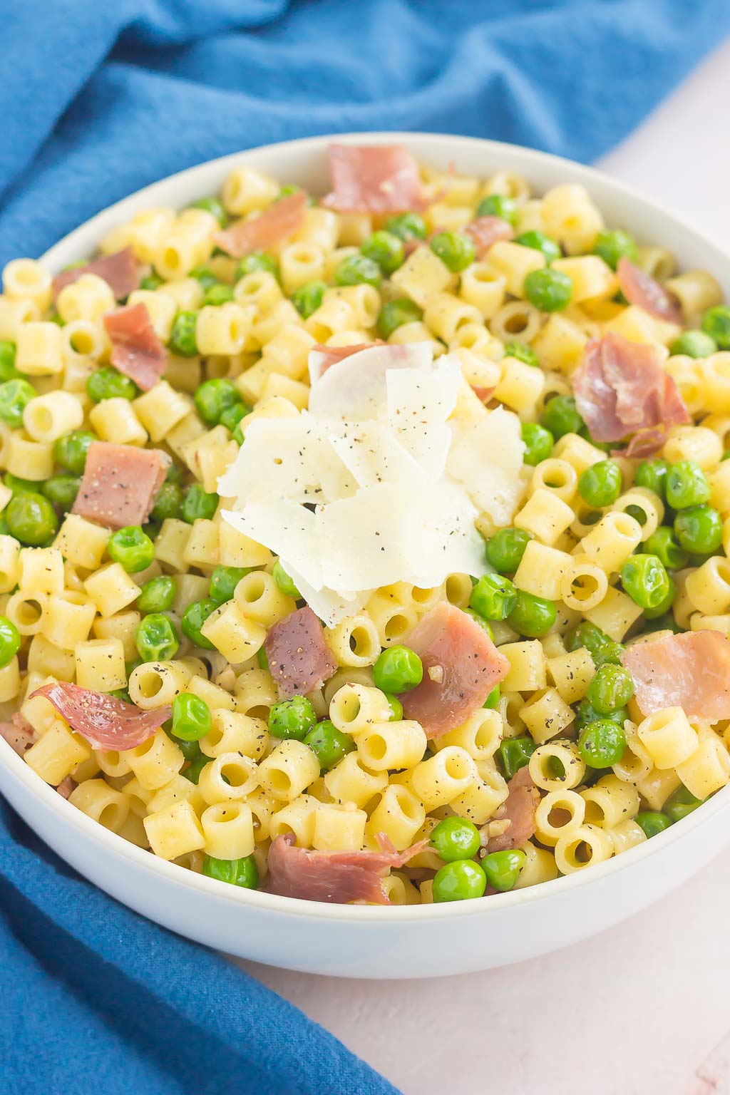 An overhead view of a bowl of peas and prosciutto pasta.