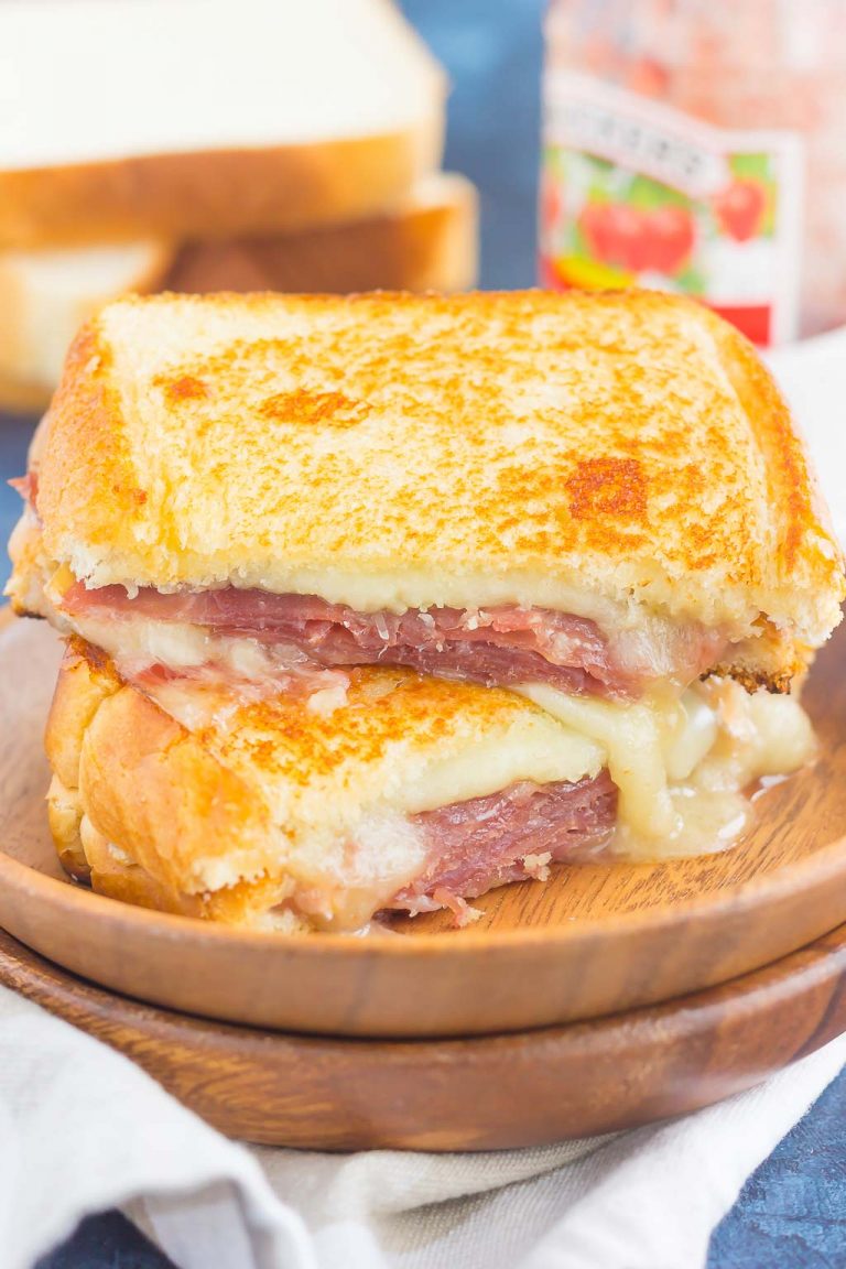 A golden grilled cheese sandwich filled with prosciutto, raspberry jam, brie, and mozzarella.