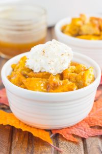 pumpkin bread pudding in a white bowl with a dollop of whipped cream