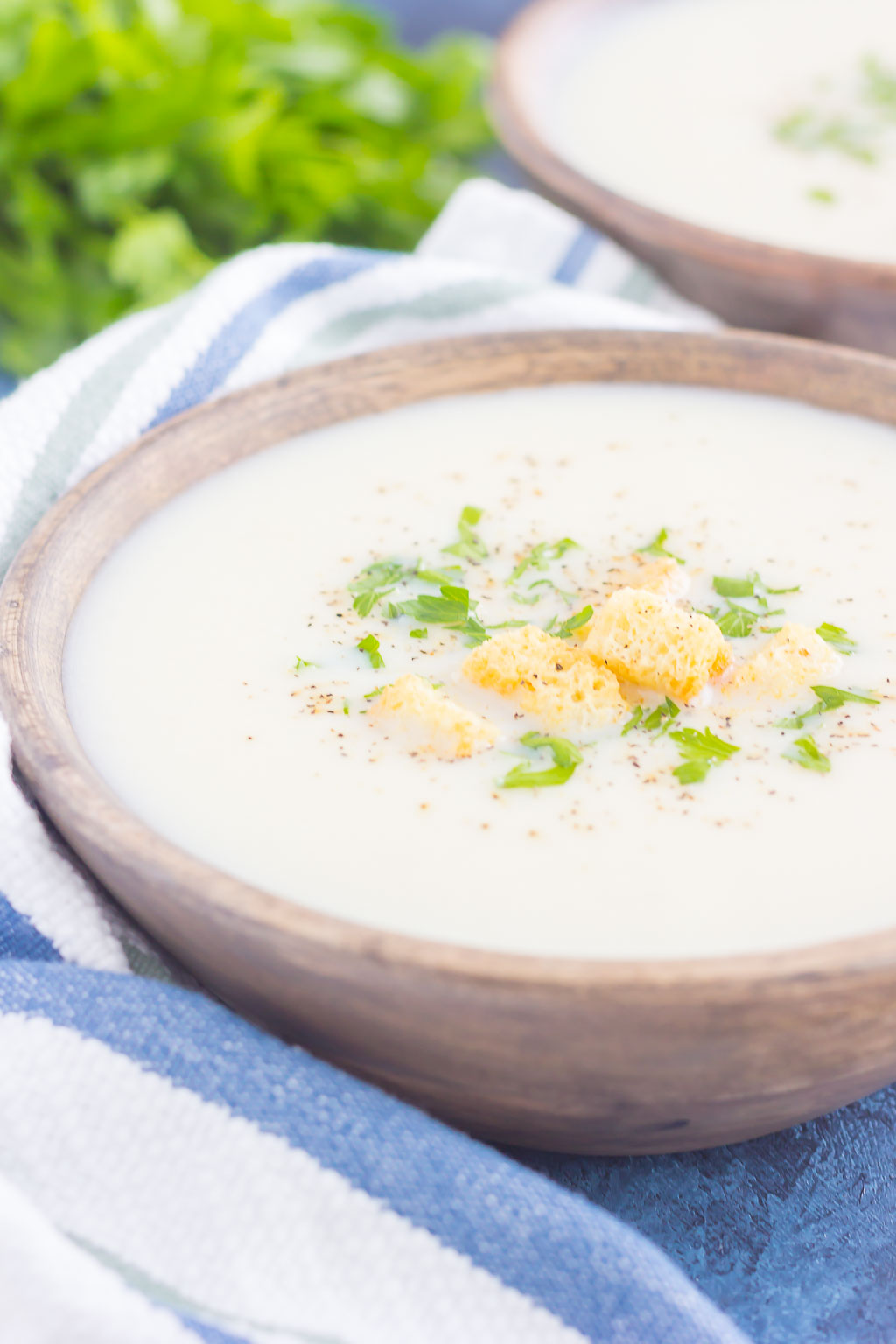 A bowl of cauliflower parmesan soup, garnished with croutons and parsley. 