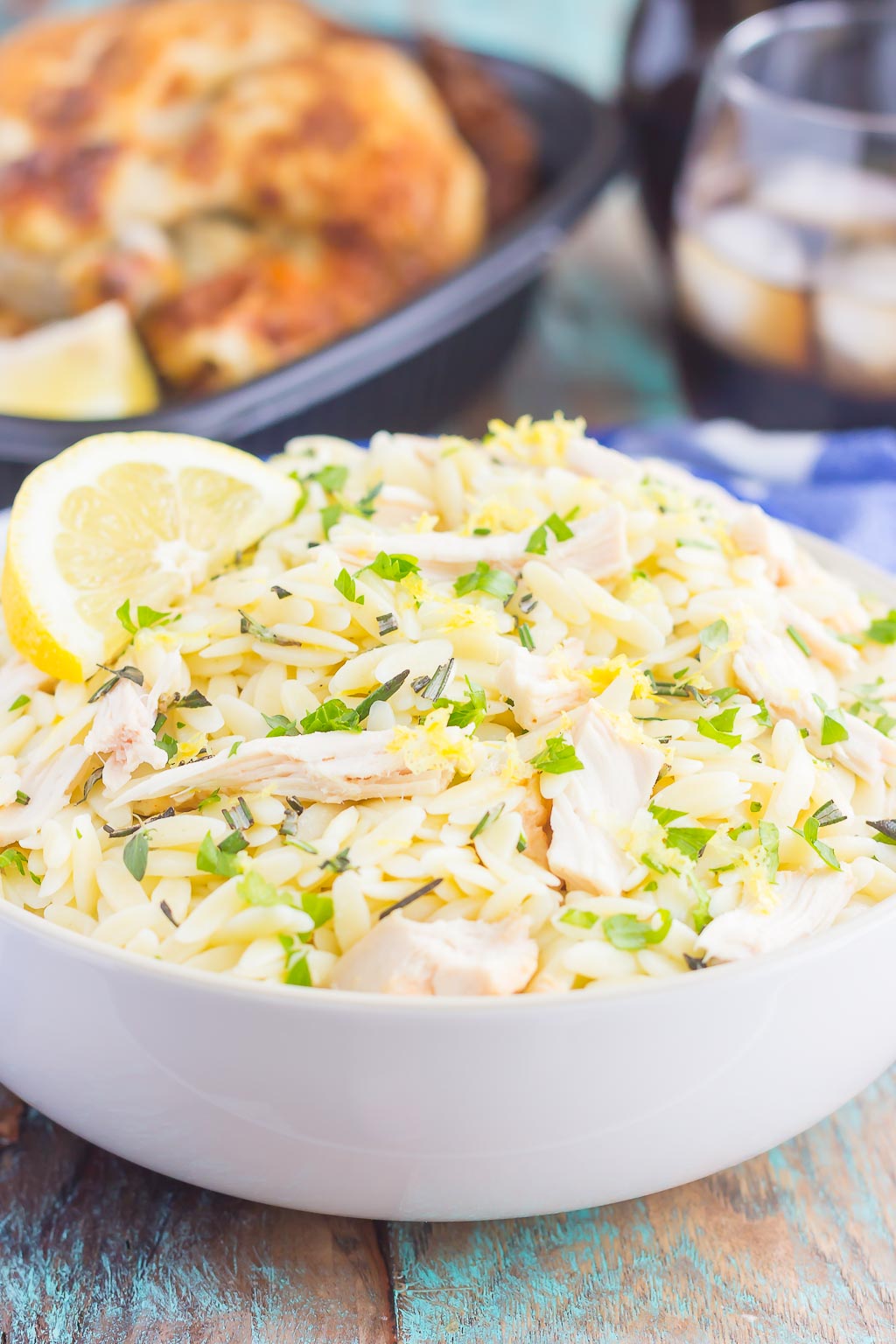 bowl of lemon orzo salad in front of a rotisserie chicken