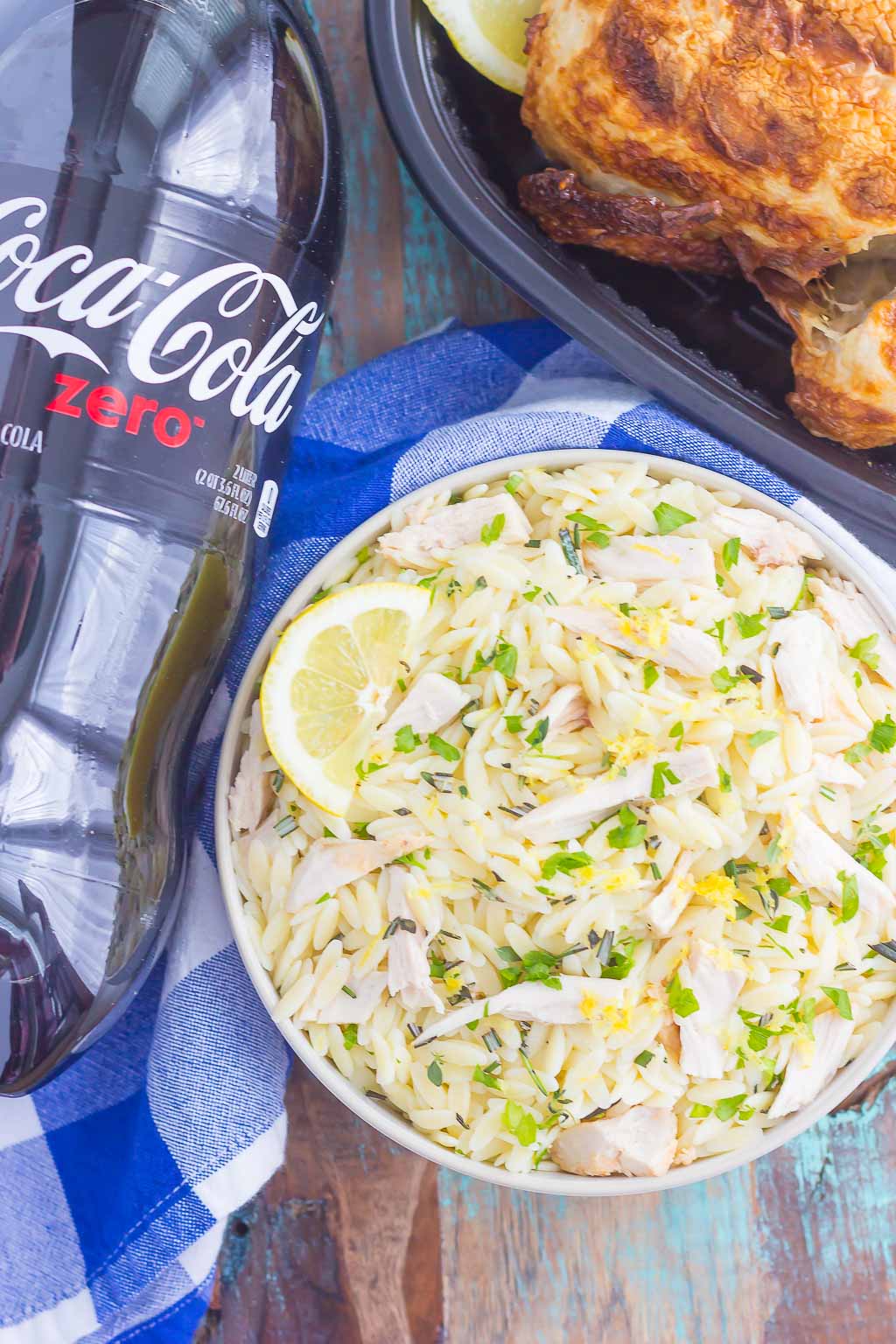 overhead shot of bowl of lemon orzo pasta salad next to bottle of coca cola and rotisserie chicken