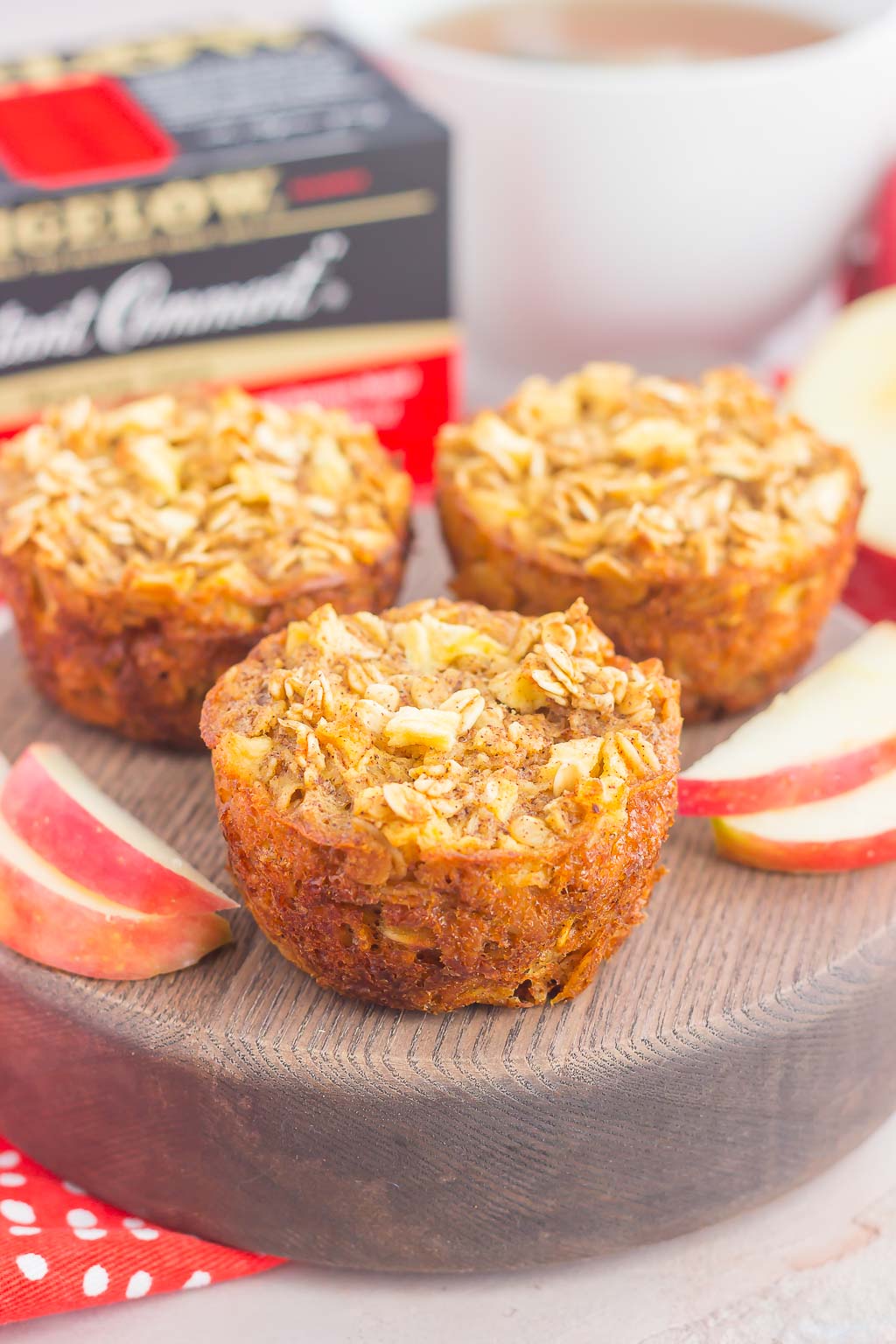 three apple cinnamon baked oatmeal cups on a wood board with apple slices