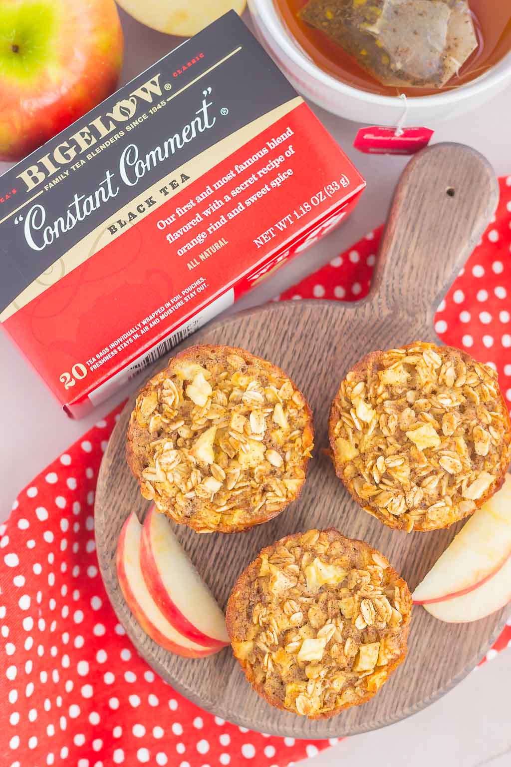 overhead view of three apple and cinnamon oatmeal cups on a wood platter next to a box of tea