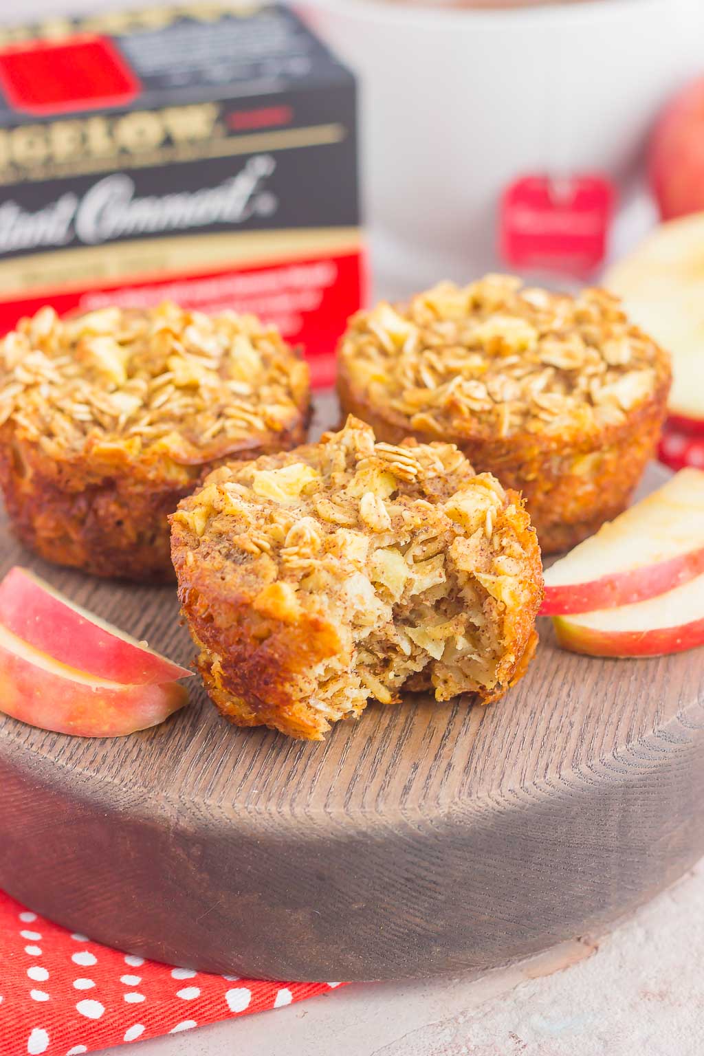 three baked oatmeal cups on a wood platter, the front one has a bite missing