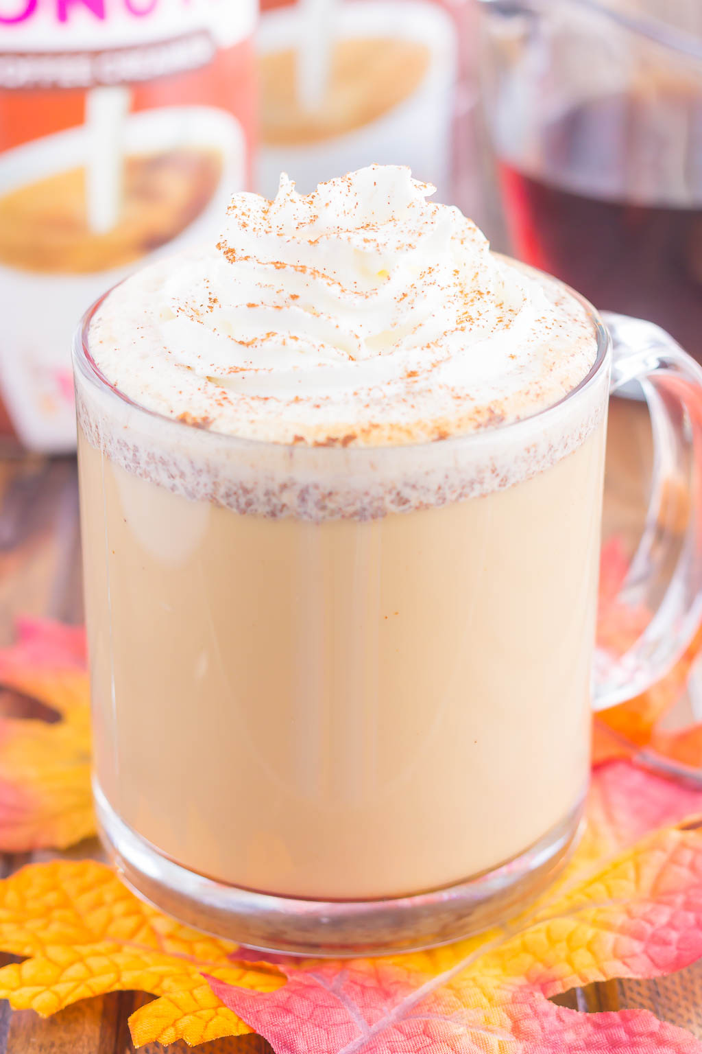 A maple latte topped with whipped cream in a glass mug. 