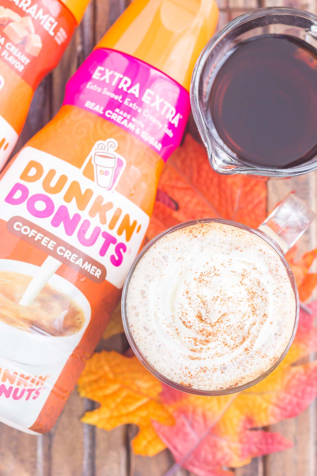 Overhead view of a maple syrup coffee drink next to a bottle of Dunkin' Donuts creamer. 
