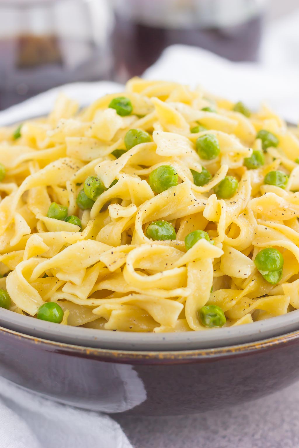buttered egg noodles with peas in a large bowl 