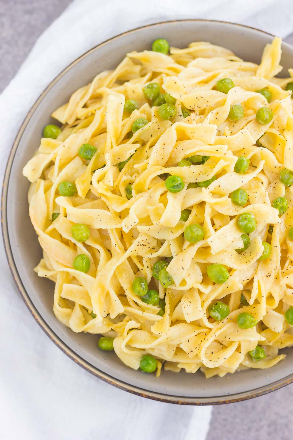 overhead view of an egg noodle side dish with peas in a large bowl 