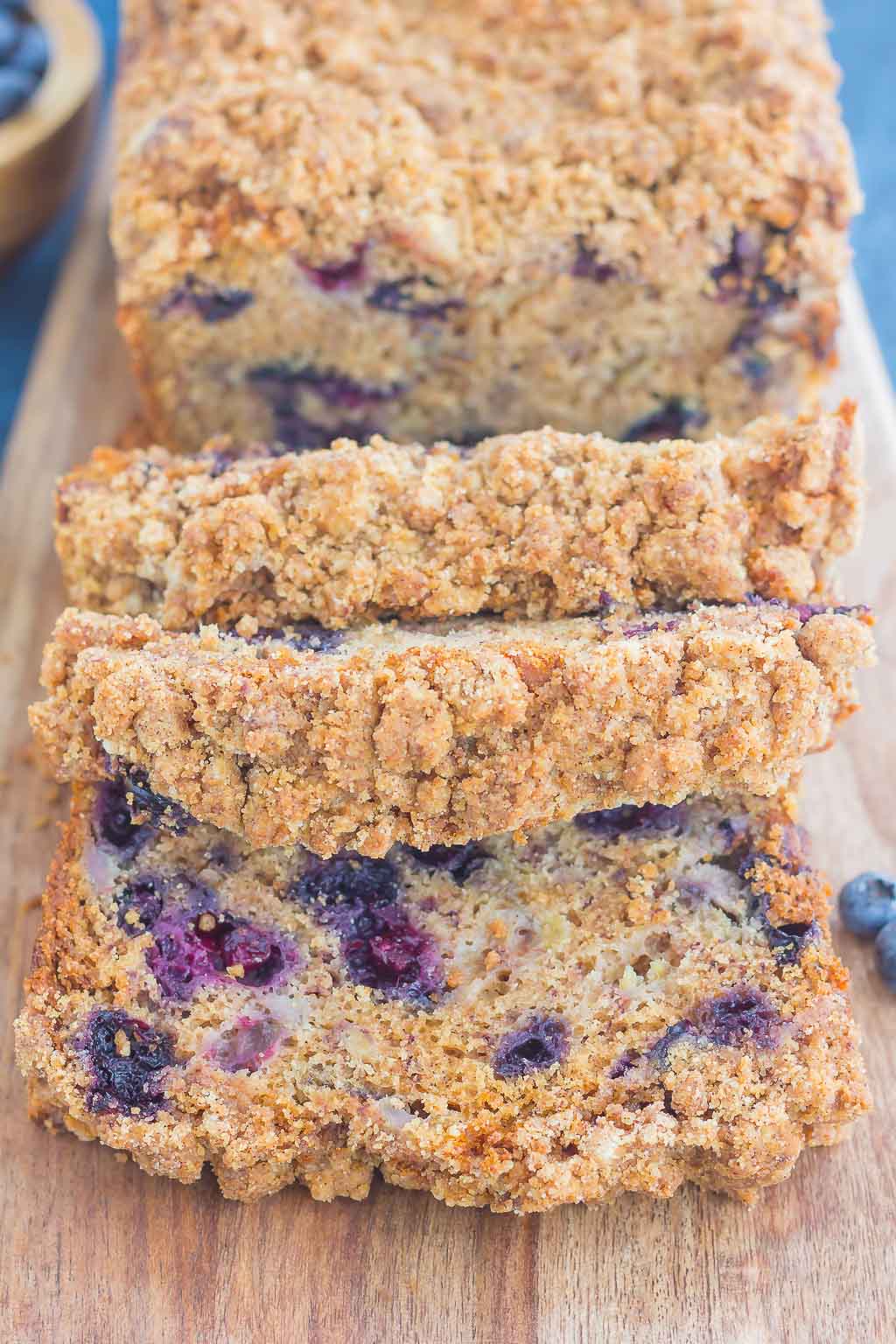 sliced loaf of blueberry banana bread on wood cutting board