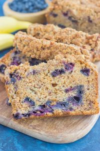 slices of blueberry banana bread on wood cutting board