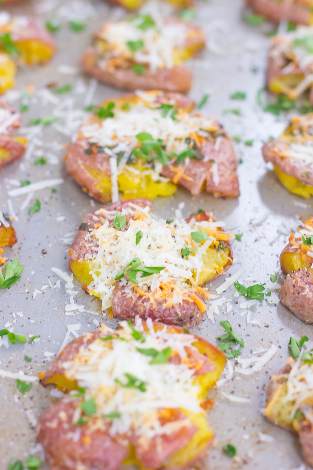 close up of garlic parmesan smashed baby red potatoes on a baking tray