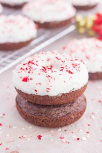 two stacked chocolate donuts with others in the background