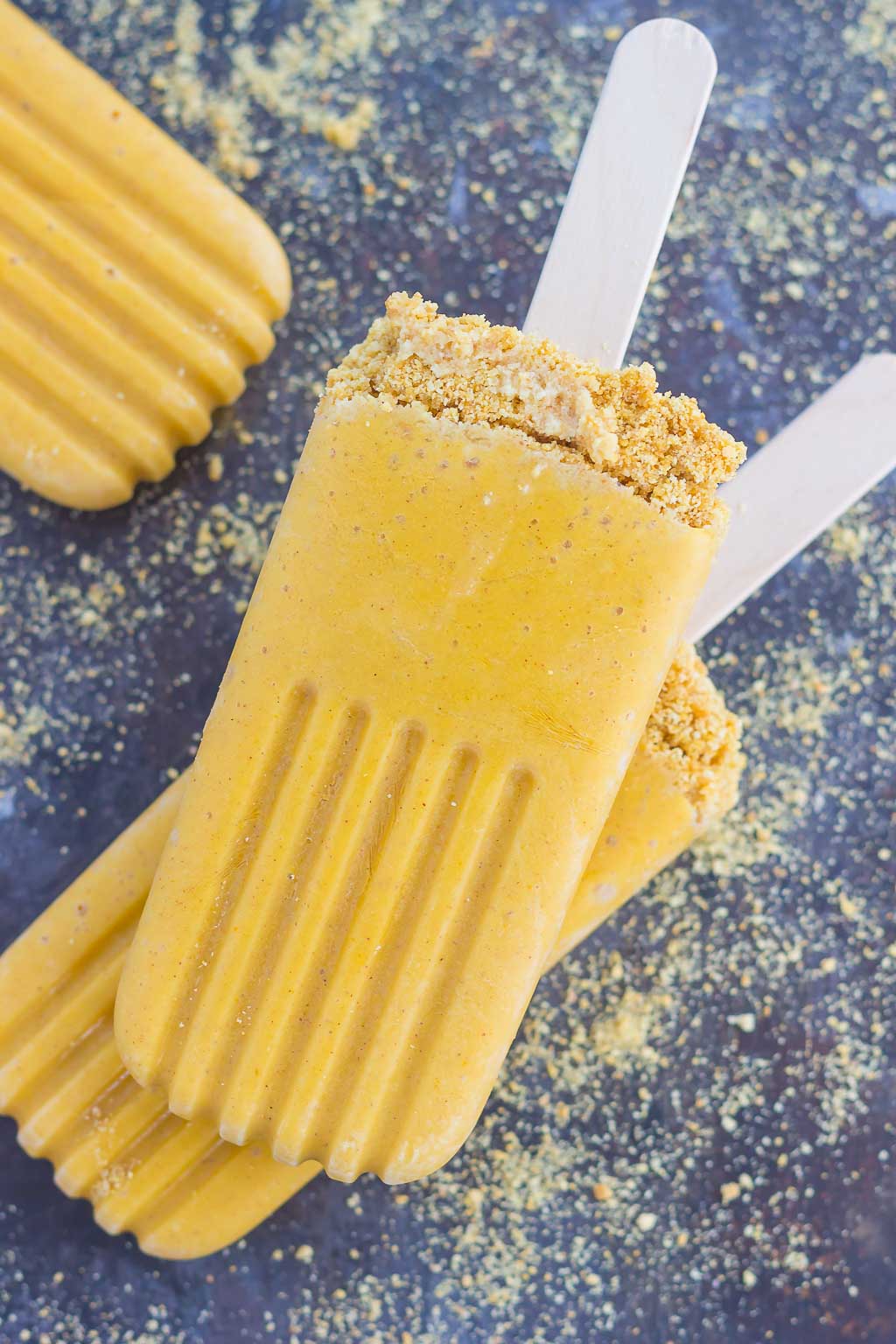 These Pumpkin Pie Pops taste just like the classic pie, but in frozen form. Sprinkled with a graham cracker crust and filled with healthier ingredients, these creamy pops are the perfect dessert for the season! #pumpkin #pumpkinpops #pumpkinpie #frozendessert #dessert #pumpkindessert #falldessert 