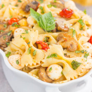 This Roasted Mushroom and Tomato Pasta Salad is a flavorful dish that comes together in minutes. Fresh mushrooms and cherry tomatoes are roasted until tender and then tossed with chickpeas, mozzarella and pasta in a light, white balsamic dressing. Bursting with flavor and perfect for a light lunch or dinner, you'll be making this pasta salad all year long!