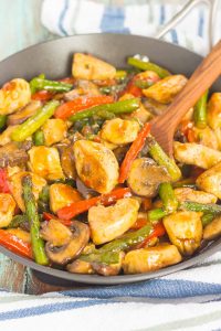 pan of honey garlic chicken stir fry with a wooden spoon