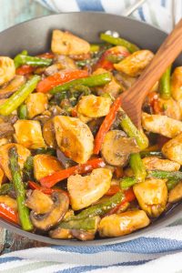 honey garlic stir-fry in a pan with a wooden spoon