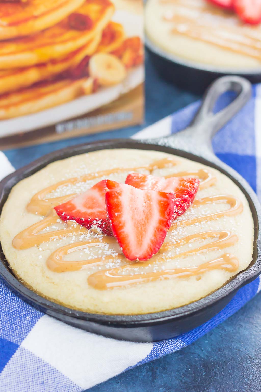 Peanut Butter and Jelly Baked Pancakes are a warm and cozy breakfast to get you going in the mornings. Fluffy, buttermilk pancake batter is swirled with sweet strawberry jelly and then baked in mini cast iron skillets. Drizzled with a sweet peanut butter syrup and topped with fresh strawberries, this easy breakfast is ready in less than 30 minutes and perfect for the whole family!