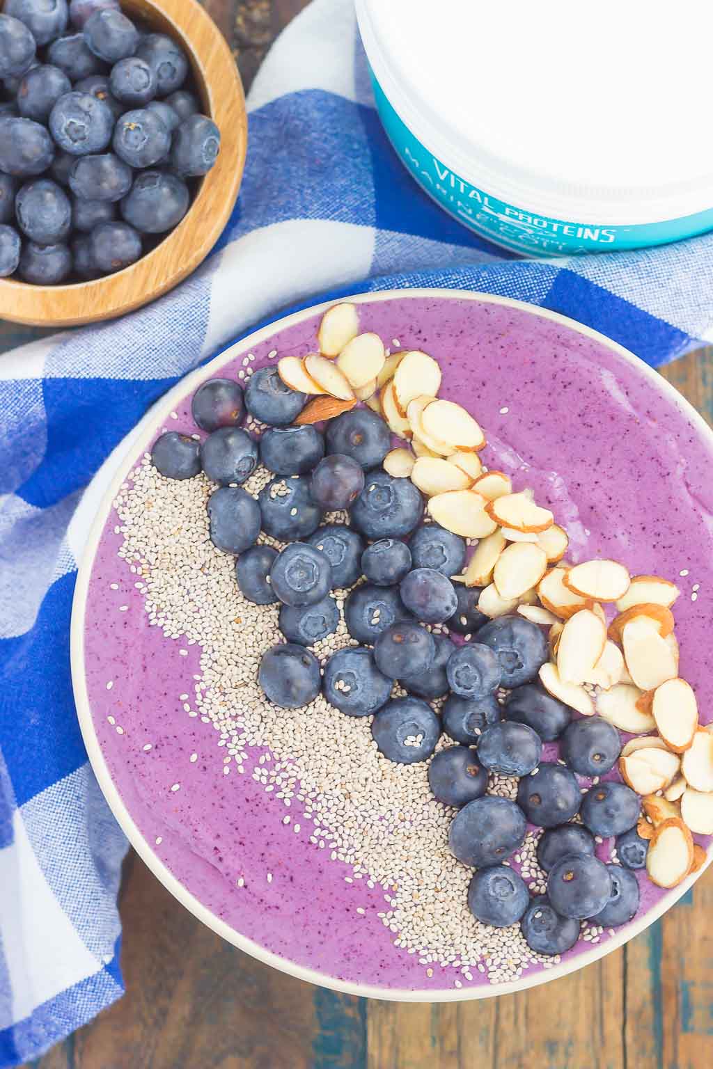 Overhead view of a blueberry and banana smoothie bowl topped with fresh blueberries, chia seeds, and sliced almonds. 