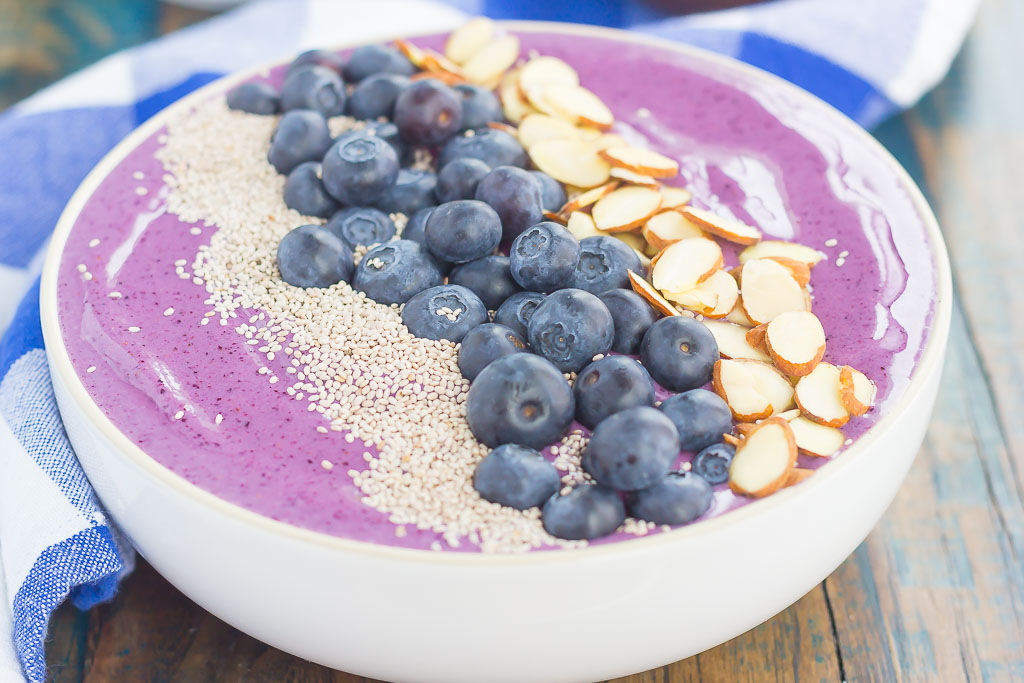 A blueberry smoothie bowl topped with fresh blueberries, chia seeds, and sliced almonds. 