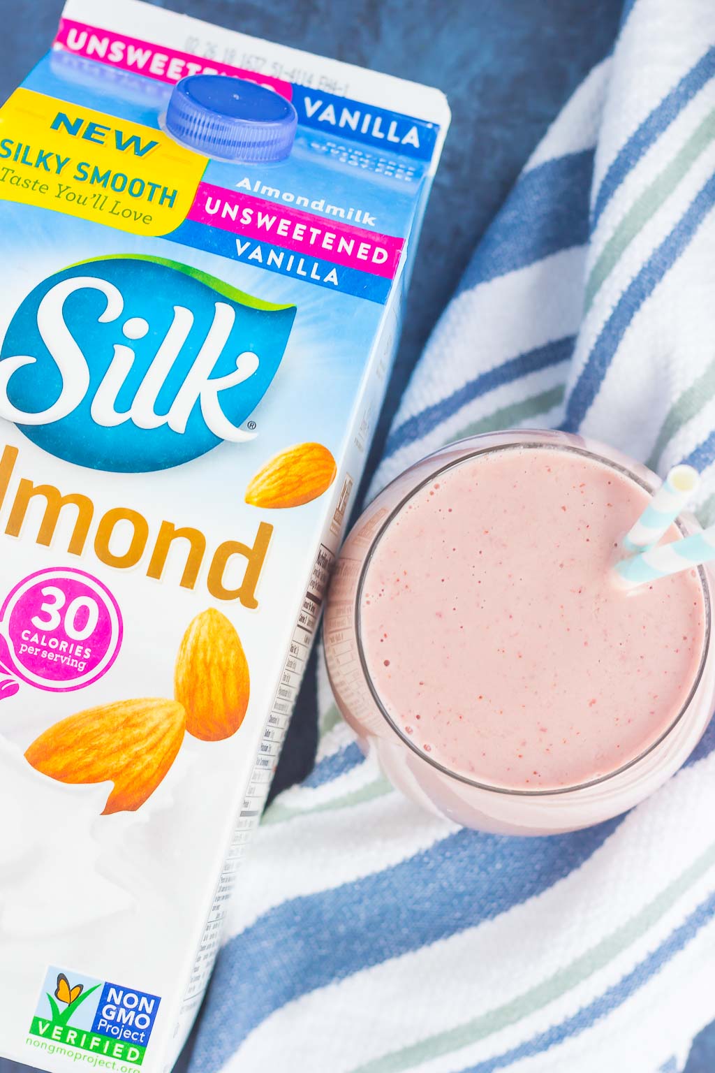 Overhead view of a mango cherry smoothie next to a carton of Silk almond milk. 