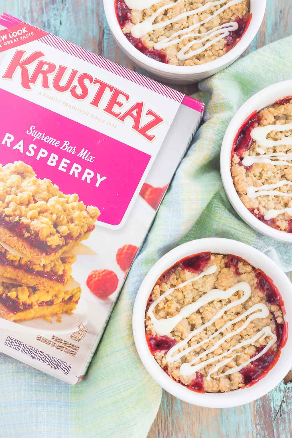 Overhead view of a box of Krusteaz raspberry bar mix next to three ramekins of raspberry crumble. 