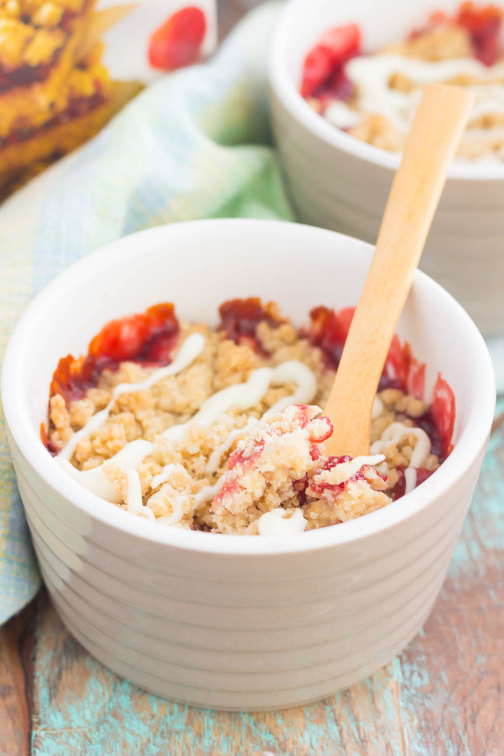 Two white ramekins of raspberry crumble. A box of Krusteaz raspberry bar mix is in the background. 