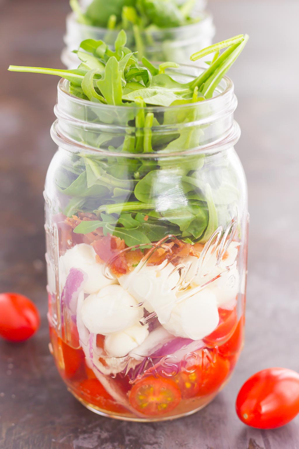 Caprese Mason Jar Salad makes a deliciously easy meal that's perfect for just about any day. Classic caprese ingredients are layered in a mason jar, along with some red onion and crisp bacon for extra flavor. Great for meal prepping and perfect as a grab-n-go lunch, you'll love the ease and taste of this classic salad that's fun to make and even better to eat!