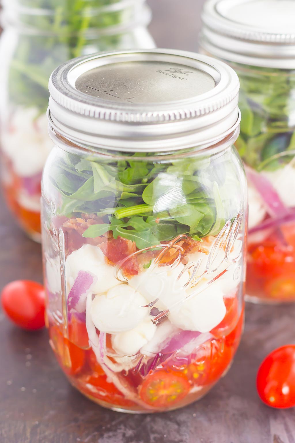 Caprese Mason Jar Salad makes a deliciously easy meal that's perfect for just about any day. Classic caprese ingredients are layered in a mason jar, along with some red onion and crisp bacon for extra flavor. Great for meal prepping and perfect as a grab-n-go lunch, you'll love the ease and taste of this classic salad that's fun to make and even better to eat!