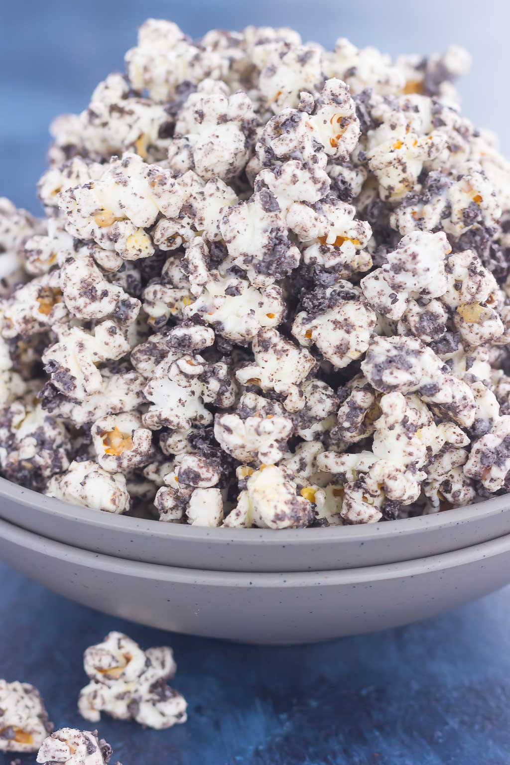 Side view of an overflowing bowl of cookies and cream popcorn.