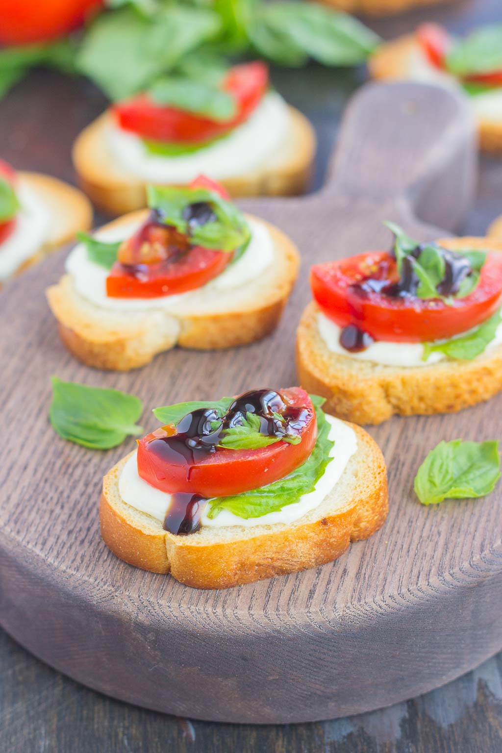 Three caprese bites on a wood charcuterie board.