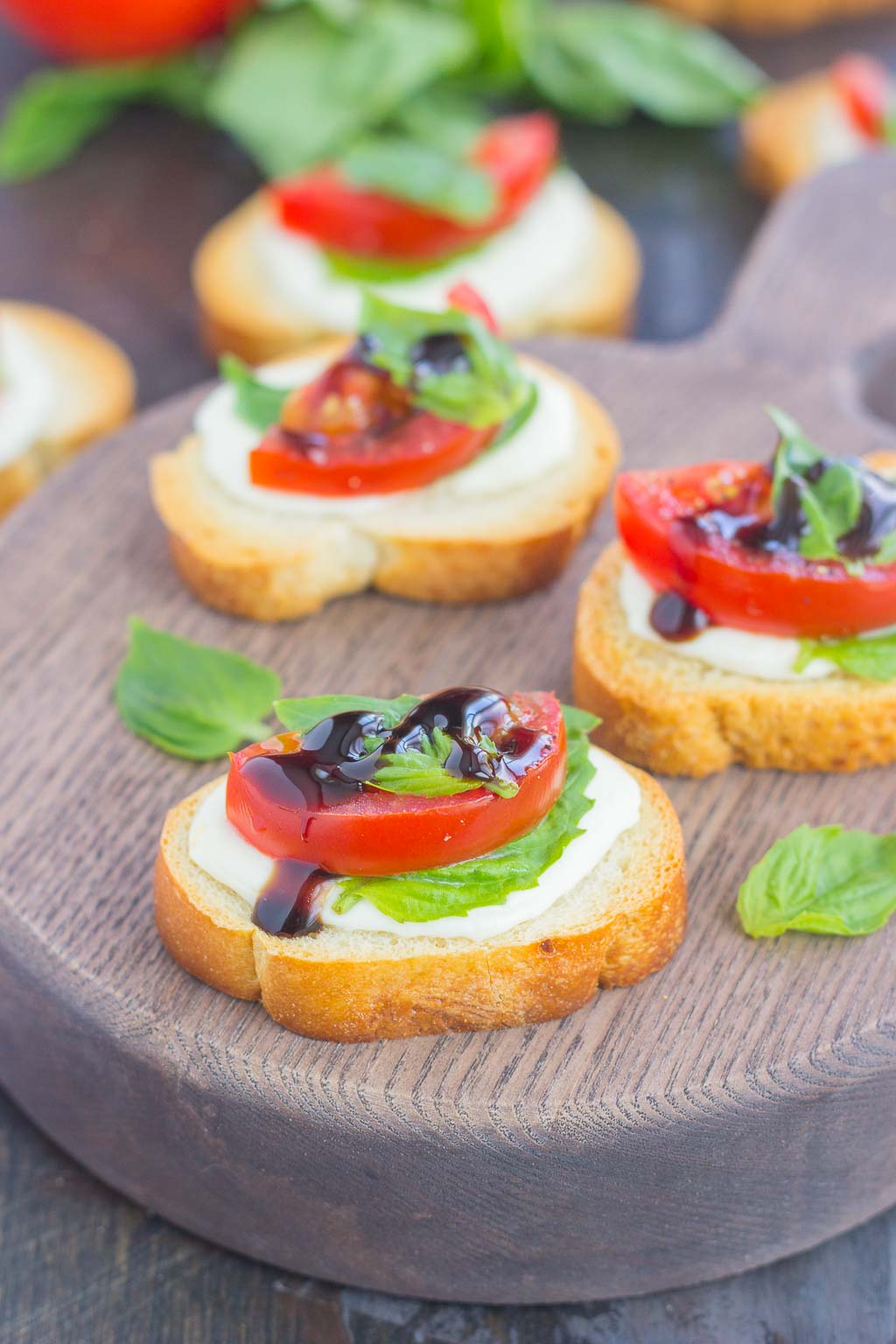 Three caprese bites on a wood charcuterie board. 