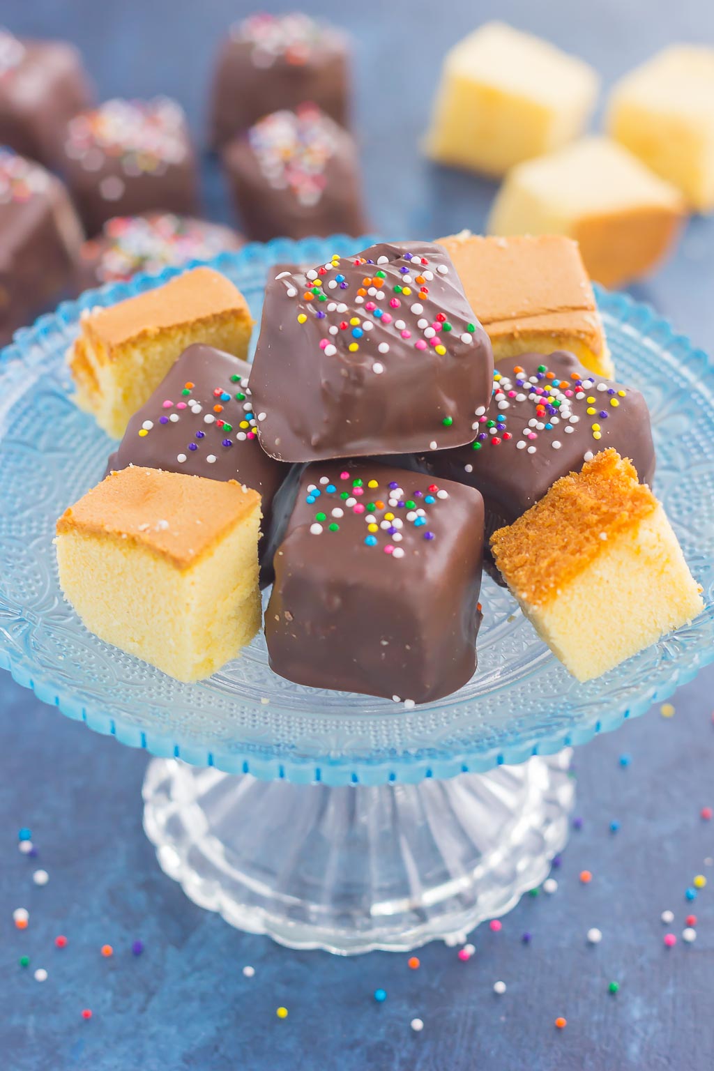 Chocolate-covered pound cake bites on a glass cake stand. 