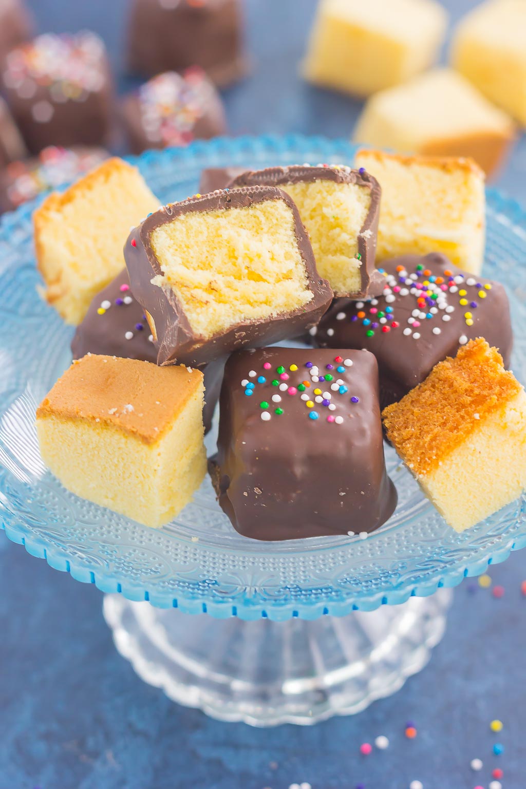 Chocolate-covered pound cake bites on a glass cake stand. 