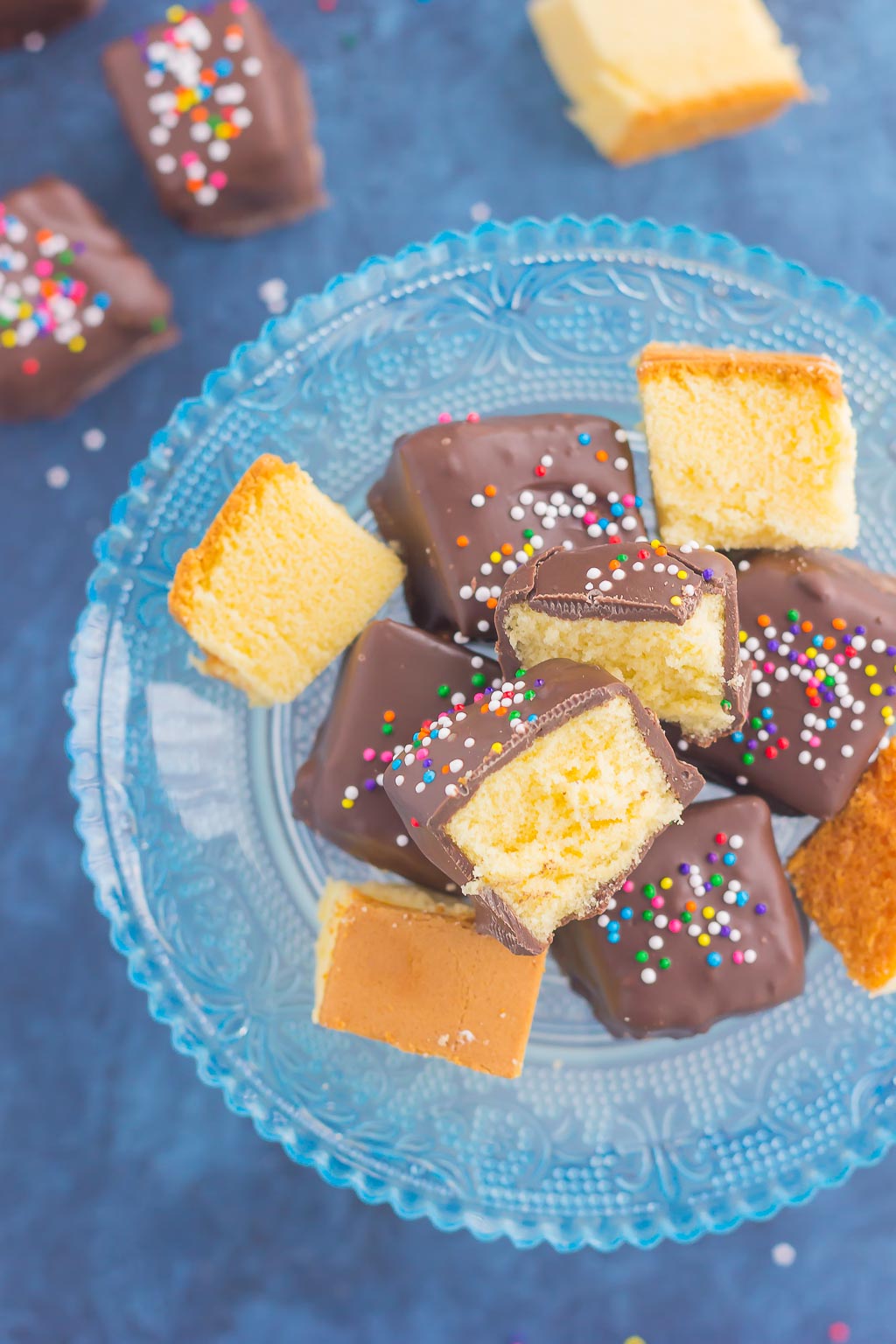 Chocolate-covered pound cake bites on a glass cake stand, seen from above. 