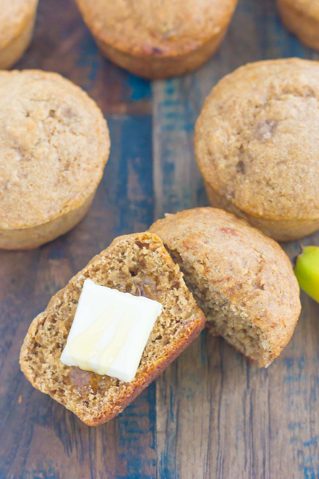 A few banana honey muffins, one has been cut in half and topped with butter. 