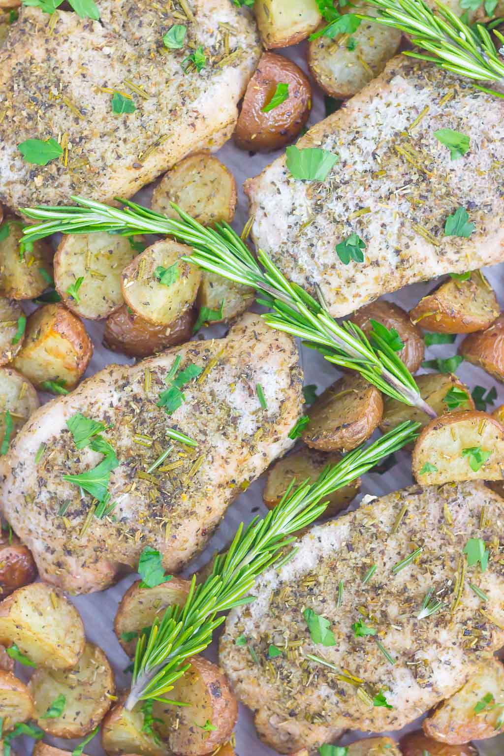 overhead view of rosemary pork chops and potatoes on a baking tray