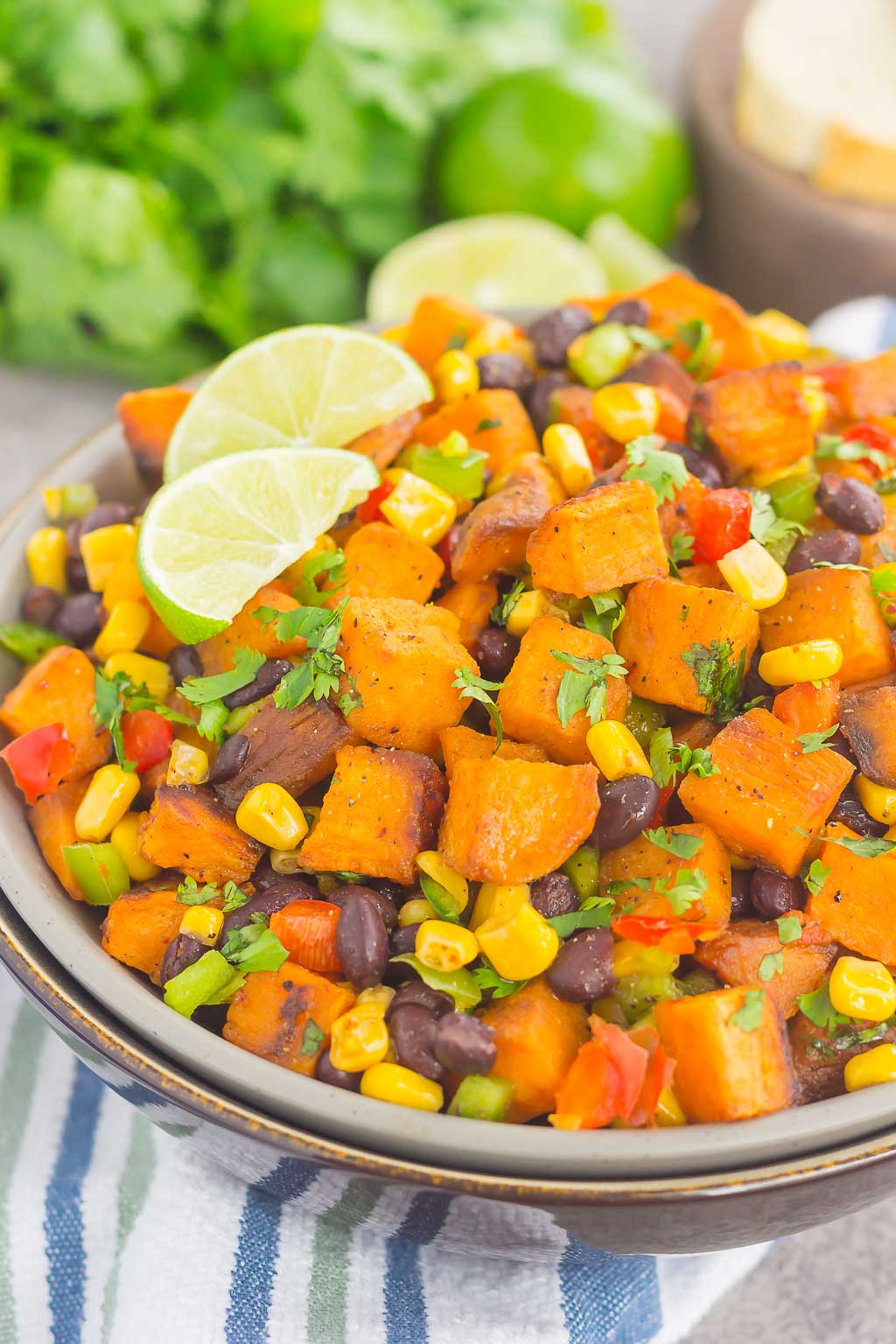 dish of roasted sweet potato salad garnished with cilantro and lime wedges