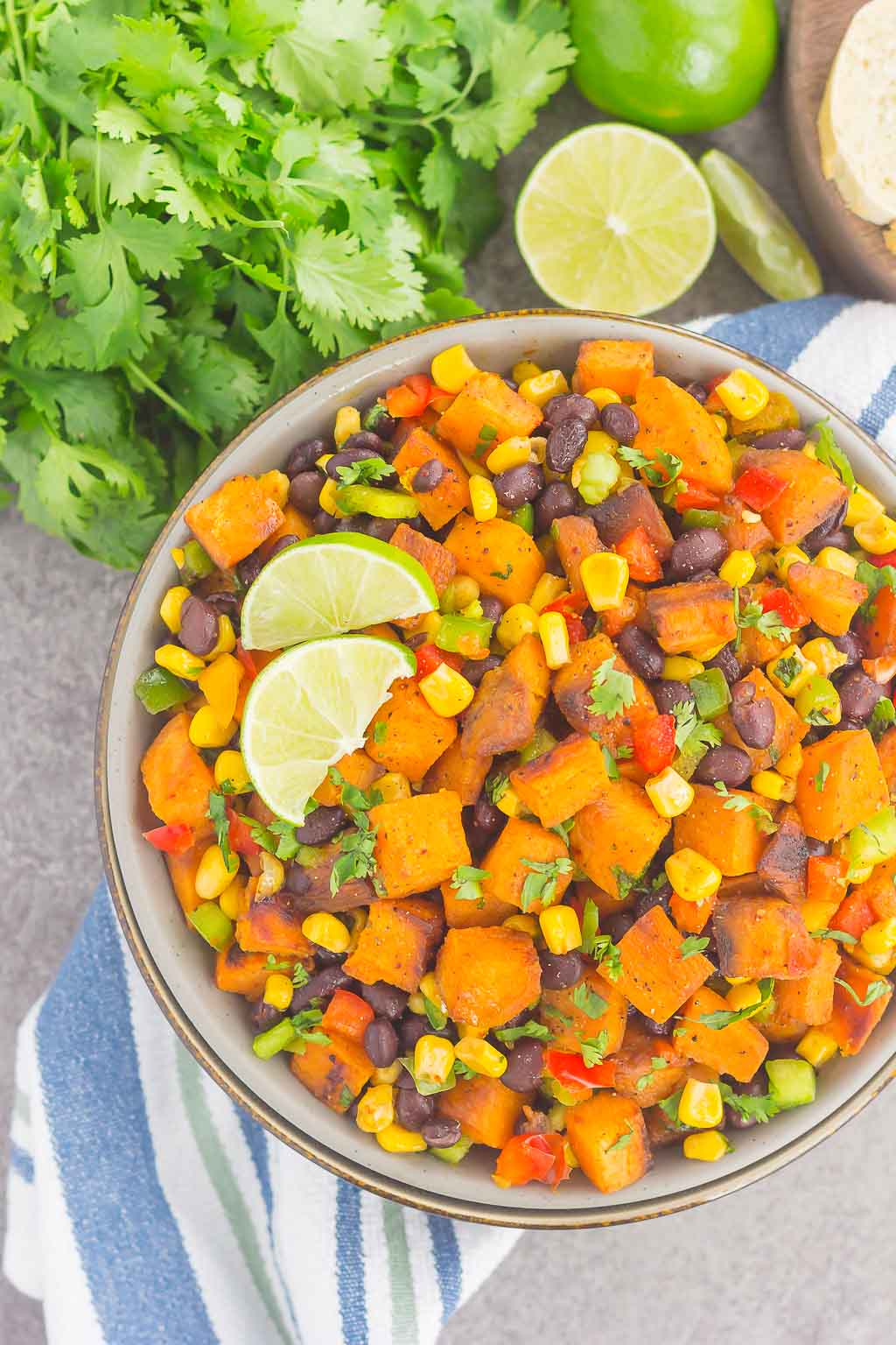 overhead view of dish of roasted sweet potato salad garnished with cilantro and lime wedges