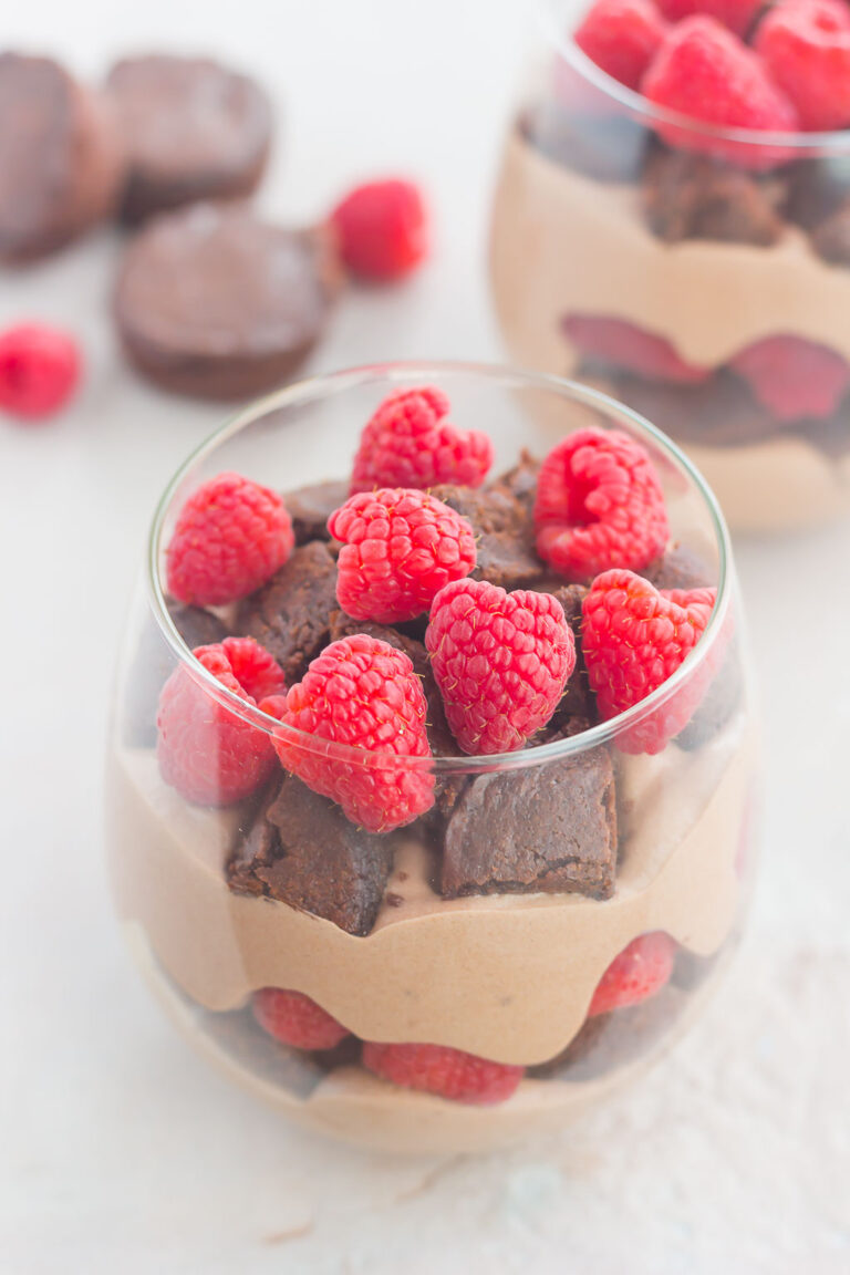Layers of brownie cubes, raspberries, and chocolate mousse in parfait glasses.