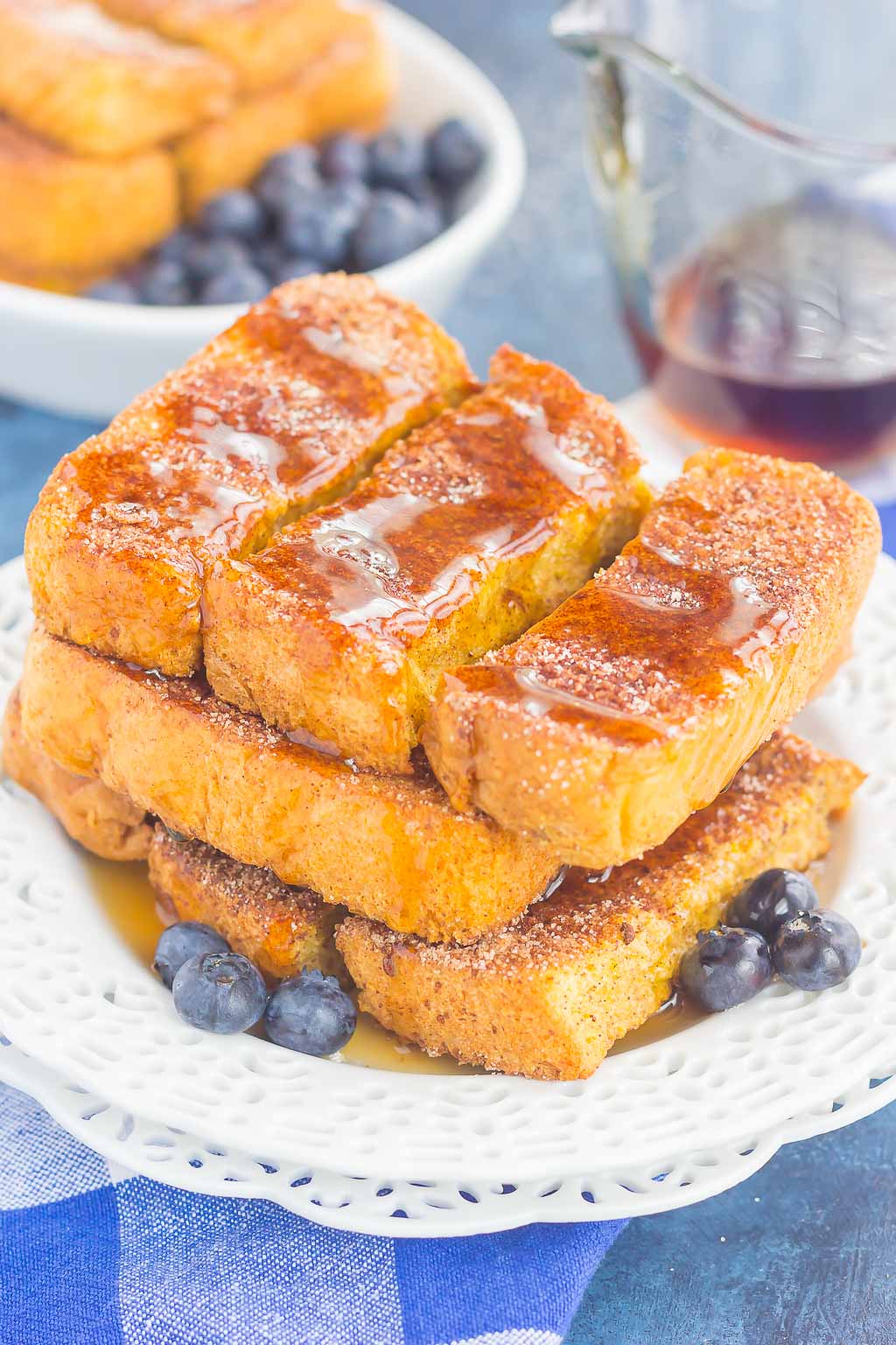 pile of baked french toast sticks on white plate topped with syrup