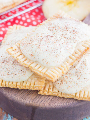 These Apple Pie Pop Tarts are an easy treat that's perfect for breakfast or dessert. Flaky pie crust surrounds sweet apple pie filling and is frosted with white chocolate and apple pie spice. Simple to make and better than the store-bought kind, you'll love the cozy taste of these homemade pop tarts!