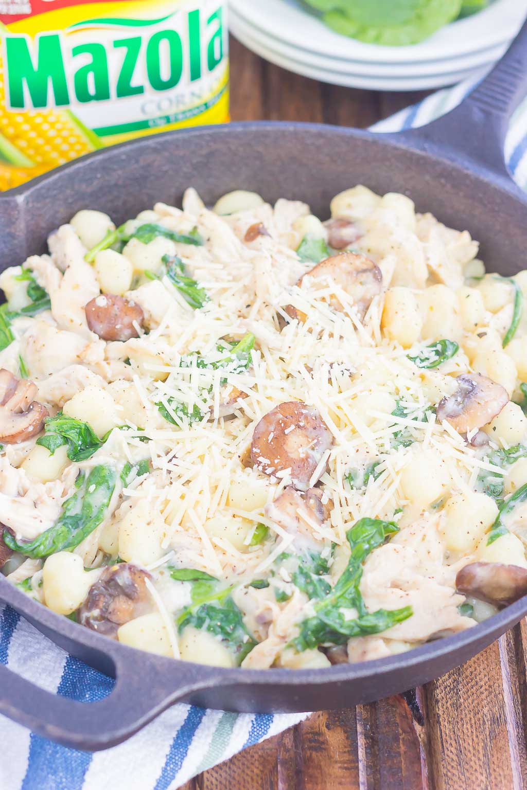 chicken and spinach gnocchi in a cast iron skillet, garnished with parmesan cheese