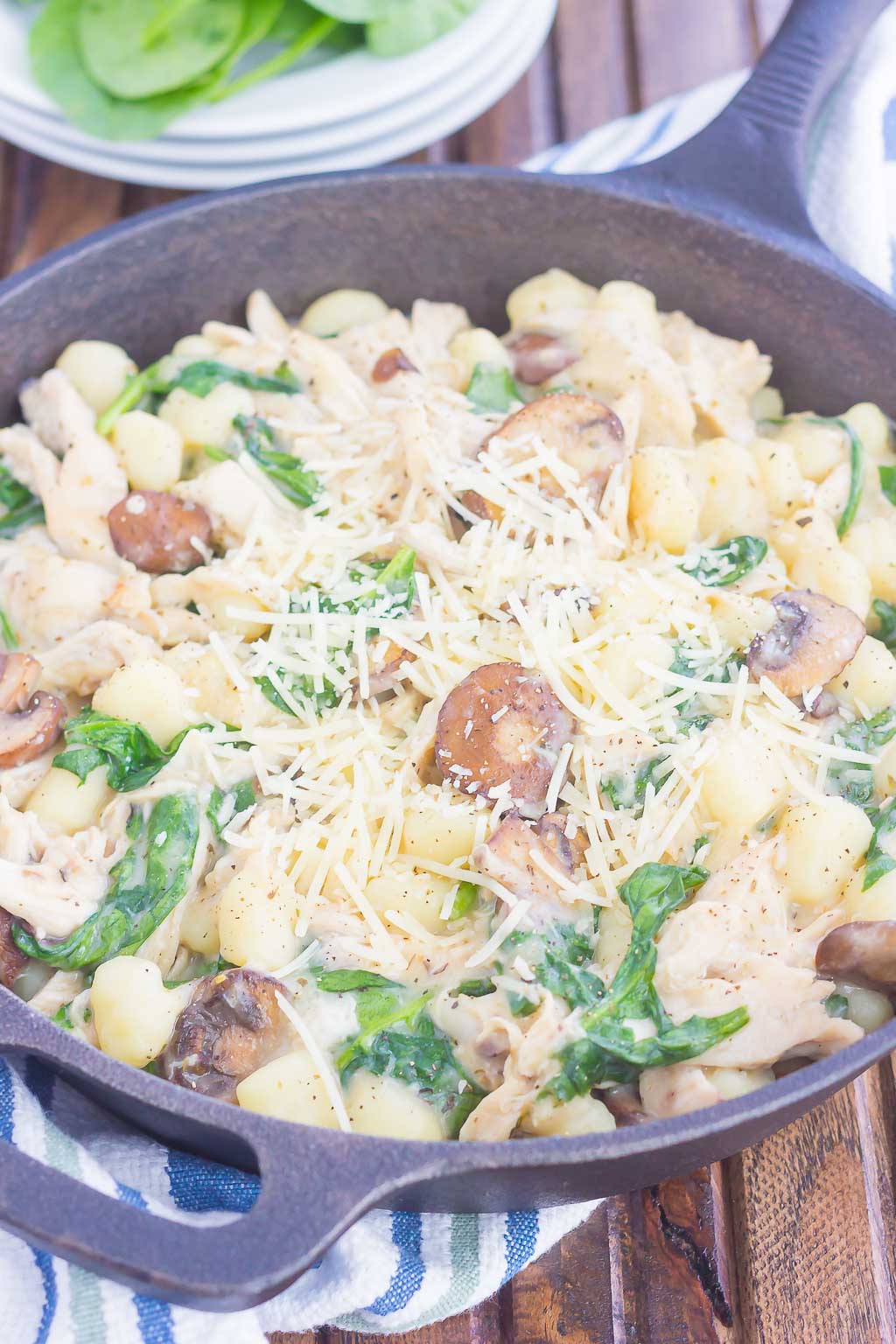 chicken and spinach gnocchi in a cast iron skillet, garnished with parmesan cheese