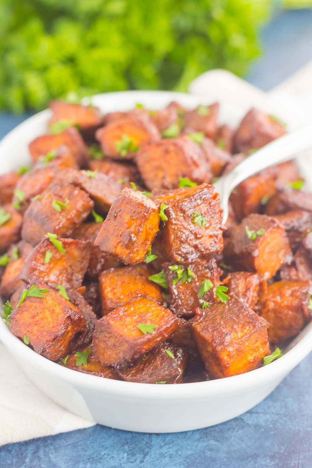 dish of baked sweet potato cubes with brown sugar garnished with parsley 