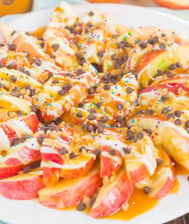 These Caramel Apple Nachos make a deliciously easy snack that's perfect for just about any time. Apple slices are drizzled with a rich caramel sauce and white chocolate, and then topped with toffee bits, chocolate chips, and sprinkles. This simple treat is ready in less than 10 minutes and is sure to be a crowd-pleaser!