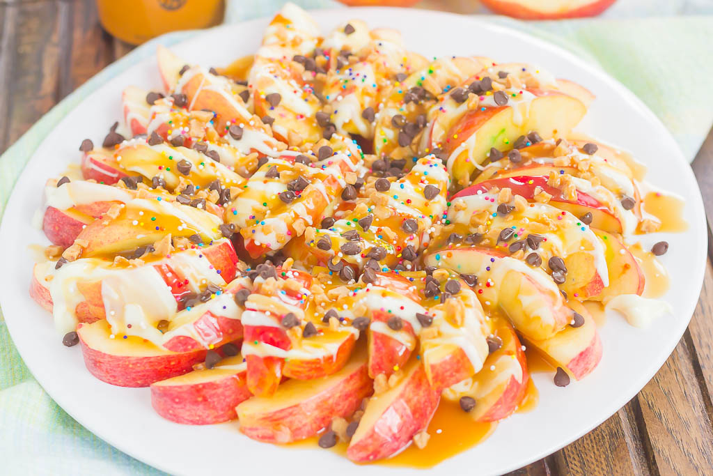 These Caramel Apple Nachos make a deliciously easy snack that's perfect for just about any time. Apple slices are drizzled with a rich caramel sauce and white chocolate, and then topped with toffee bits, chocolate chips, and sprinkles. This simple treat is ready in less than 10 minutes and is sure to be a crowd-pleaser!