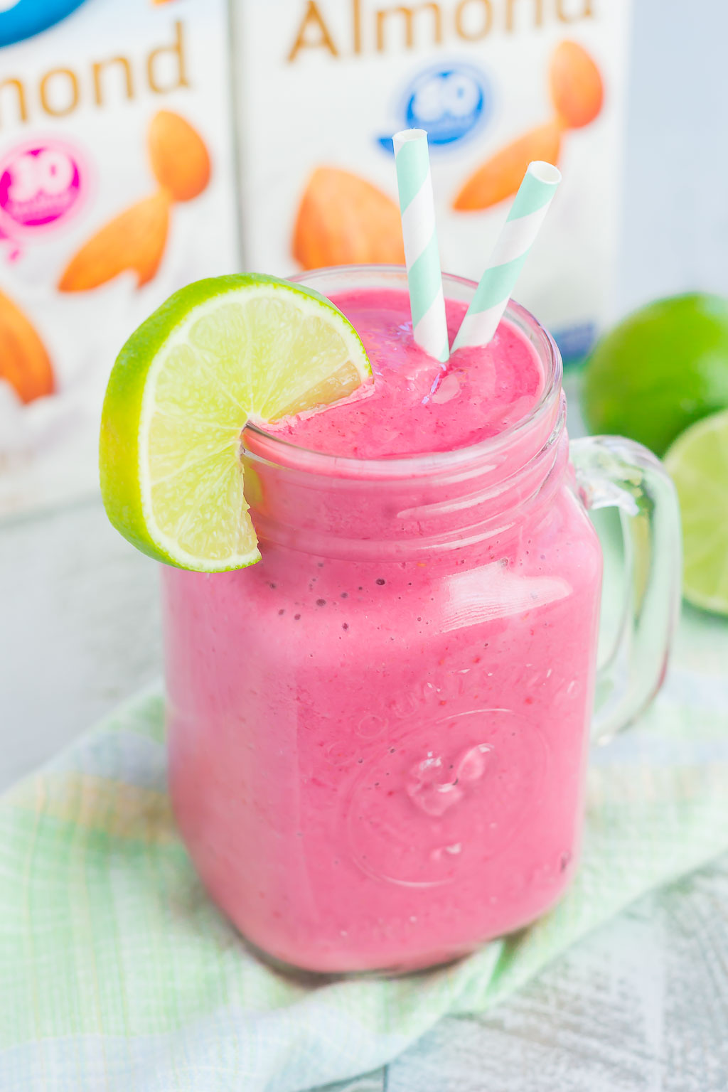 lime raspberry smoothie in mason jar with two straws